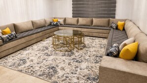 A modern living room with a sectional sofa, a glass coffee table, and a patterned rug. - Residence La perle de l'atlas (Marrakech)