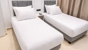 A hotel room with two single beds, a nightstand, a phone, and a curtain. - Residence La perle de l'atlas (Marrakech)