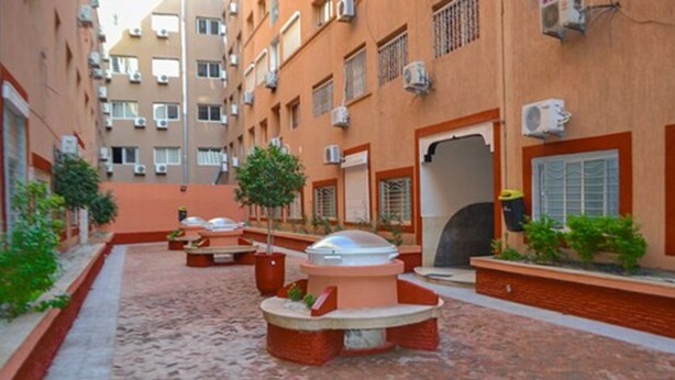 A courtyard with outdoor seating, a covered area, and a building with multiple air conditioning units. - Residence La perle de l'atlas (Marrakech)