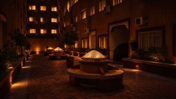 A courtyard with a central seating area, surrounded by buildings with multiple windows and air conditioning units.