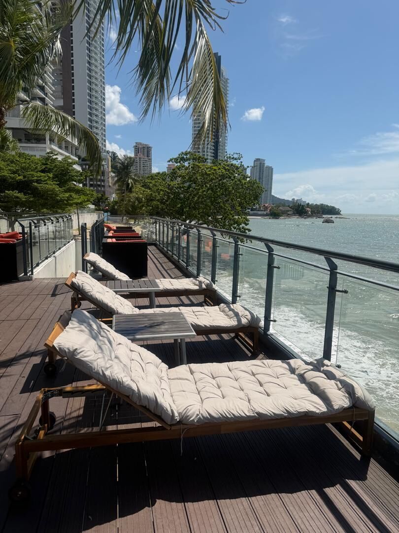 A deck with sun loungers, a railing, and a view of the water.