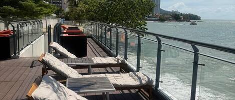 A deck with sun loungers, a railing, and a view of the water.