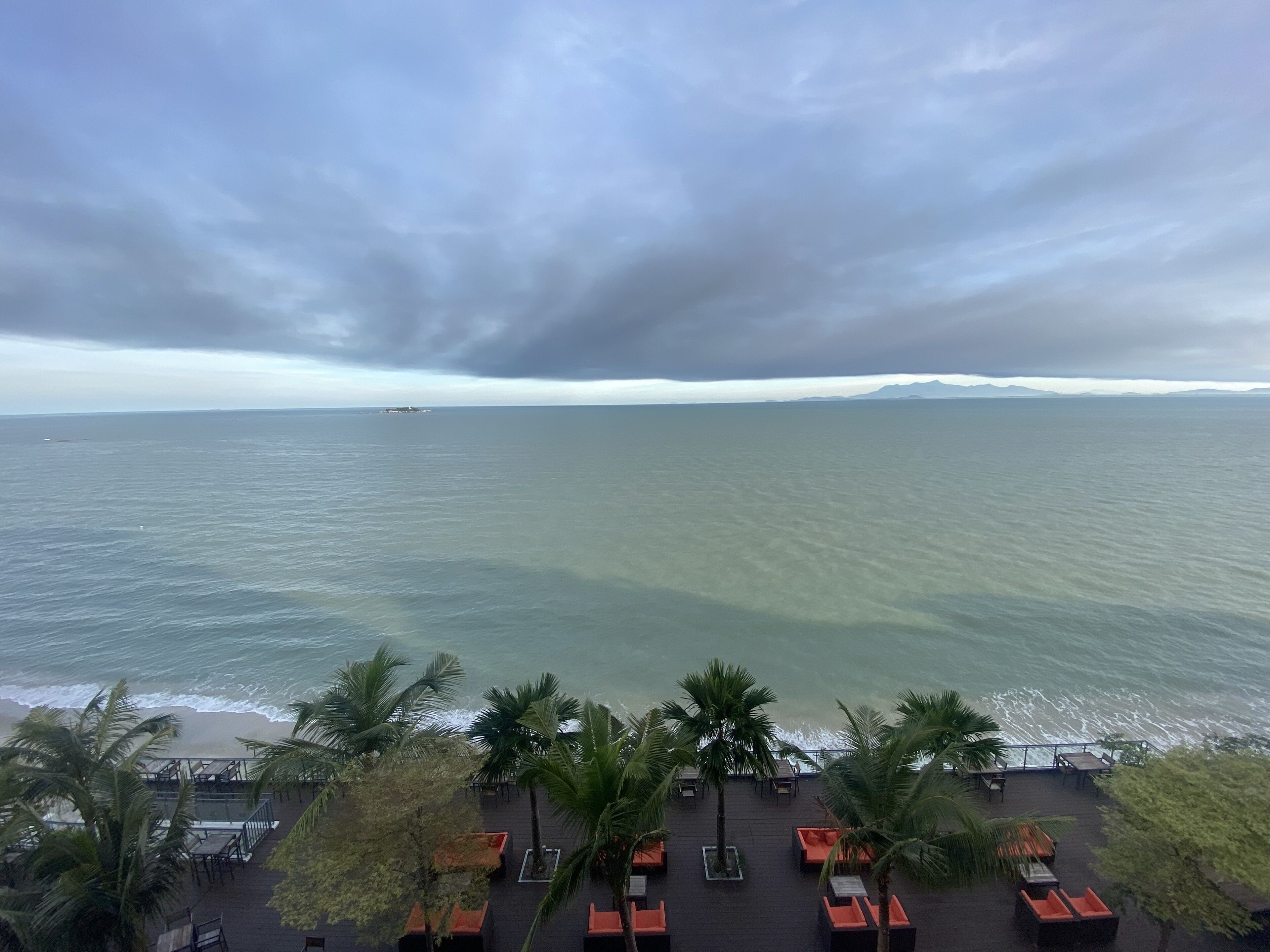 A beachside resort with a view of the ocean and distant mountains.