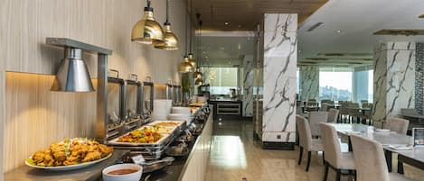 A buffet area with multiple serving stations, a long counter, and a seating area with tables and chairs.
