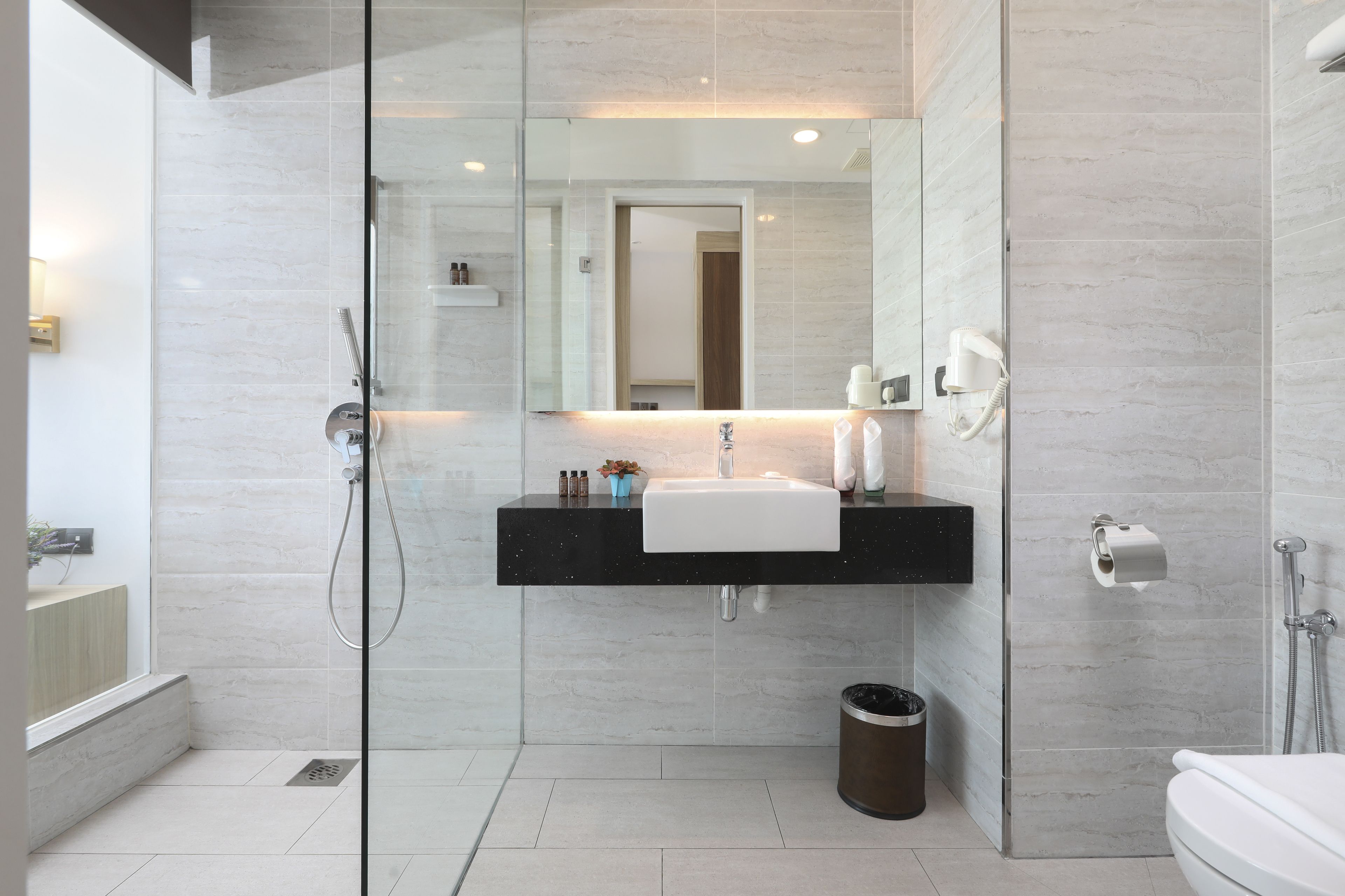 Une salle de bain moderne avec une douche à parois de verre, un lavabo blanc et des toilettes.