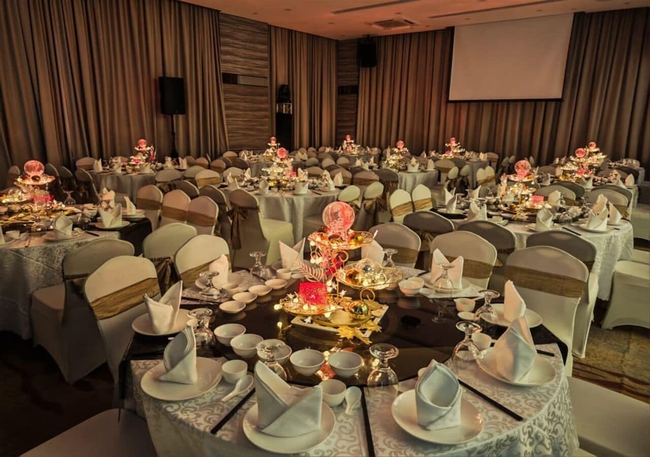 A banquet hall with round tables set for a formal event, each with a centerpiece, chairs, and table settings.