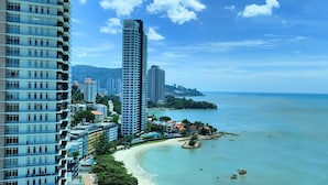 A coastal cityscape with high-rise buildings, a beach, and a clear blue sky. - Hompton by the Beach Penang (George Town)