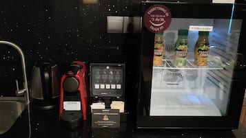 A minibar with a refrigerator containing beverages, a coffee machine, and a water dispenser.