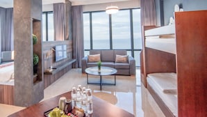 A modern hotel room with a large window, a sofa, a coffee table, and a bed. - Hompton by the Beach Penang (George Town)