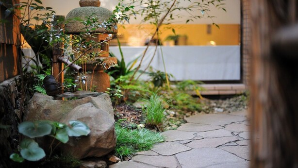 A garden with a stone pathway, rocks, and greenery. - Hachioji Sky Hotel (Hachioji)