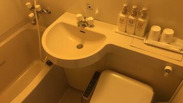A bathroom with a bathtub, a sink, and a toilet. There are toiletries on the sink counter.