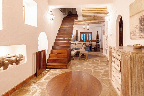 Un escalier menant à une salle à manger dotée d’un plancher en bois et d’un mur en pierre.