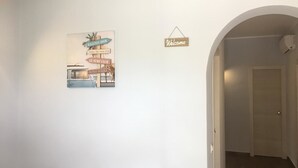 A hallway with a welcome sign and a wall-mounted artwork depicting a vintage car and signs. - Profumo di Zagara (Corigliano-Rossano)