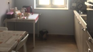 A small kitchen with a window, a table, and a chair. - Profumo di Zagara (Corigliano-Rossano)