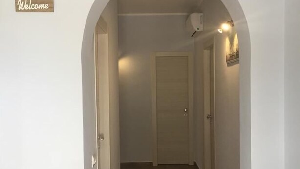 A hallway with a wooden floor, a white door at the end, and a 'Welcome' sign on the left. - Profumo di Zagara (Corigliano-Rossano)