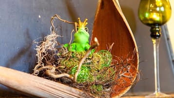 A wooden nesting box with a green frog figurine and a wine glass.