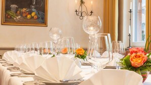 Une table à manger dressée avec des nappes blanches, de nombreux verres à vin et des centres de table floraux.