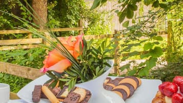 Una mesa al aire libre con varios postres y un arreglo floral.