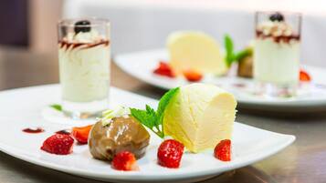 A dessert plate with ice cream, strawberries, and a mint leaf garnish.