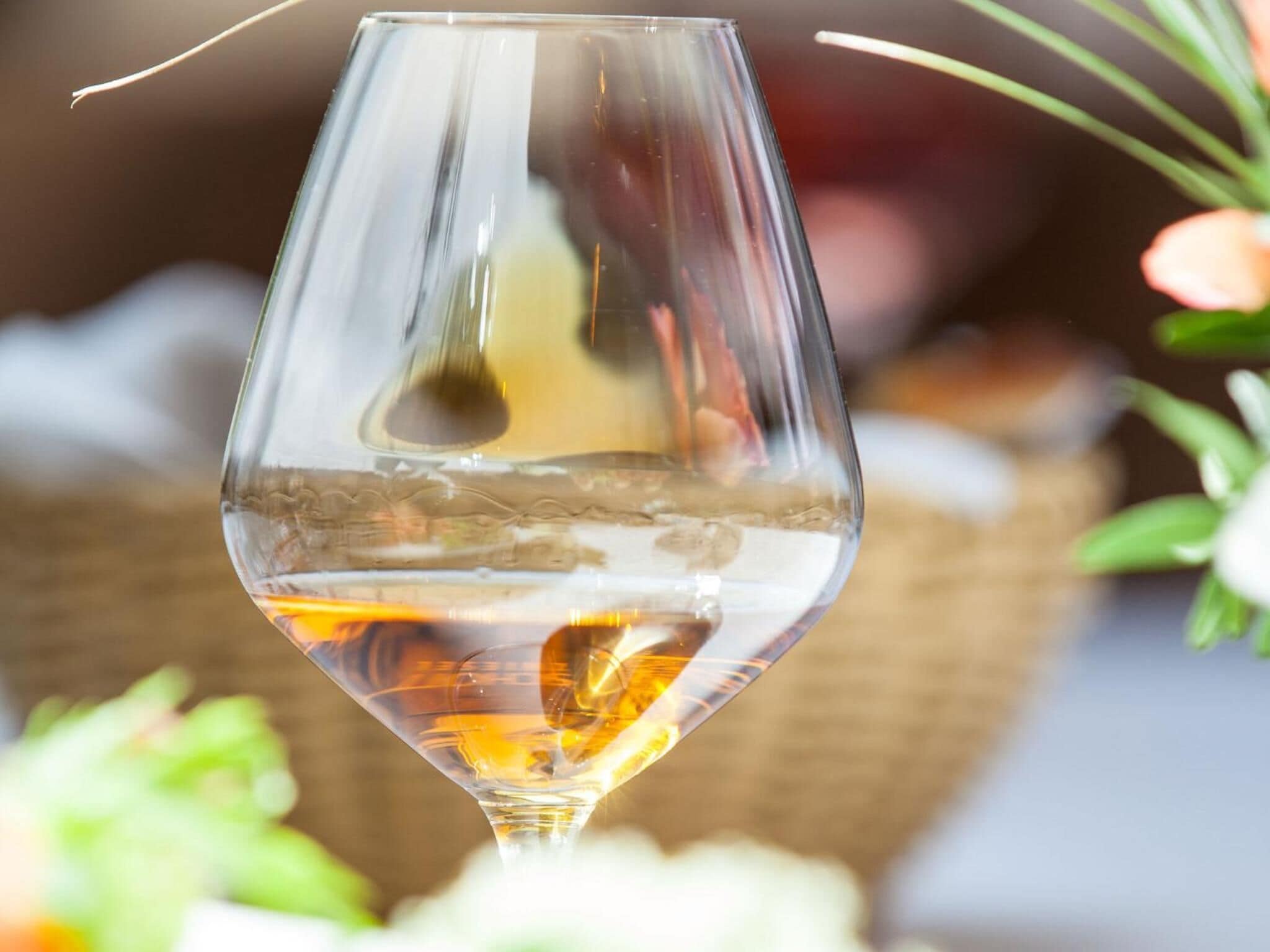 Una copa de vidrio transparente con un líquido dorado, posiblemente vino.