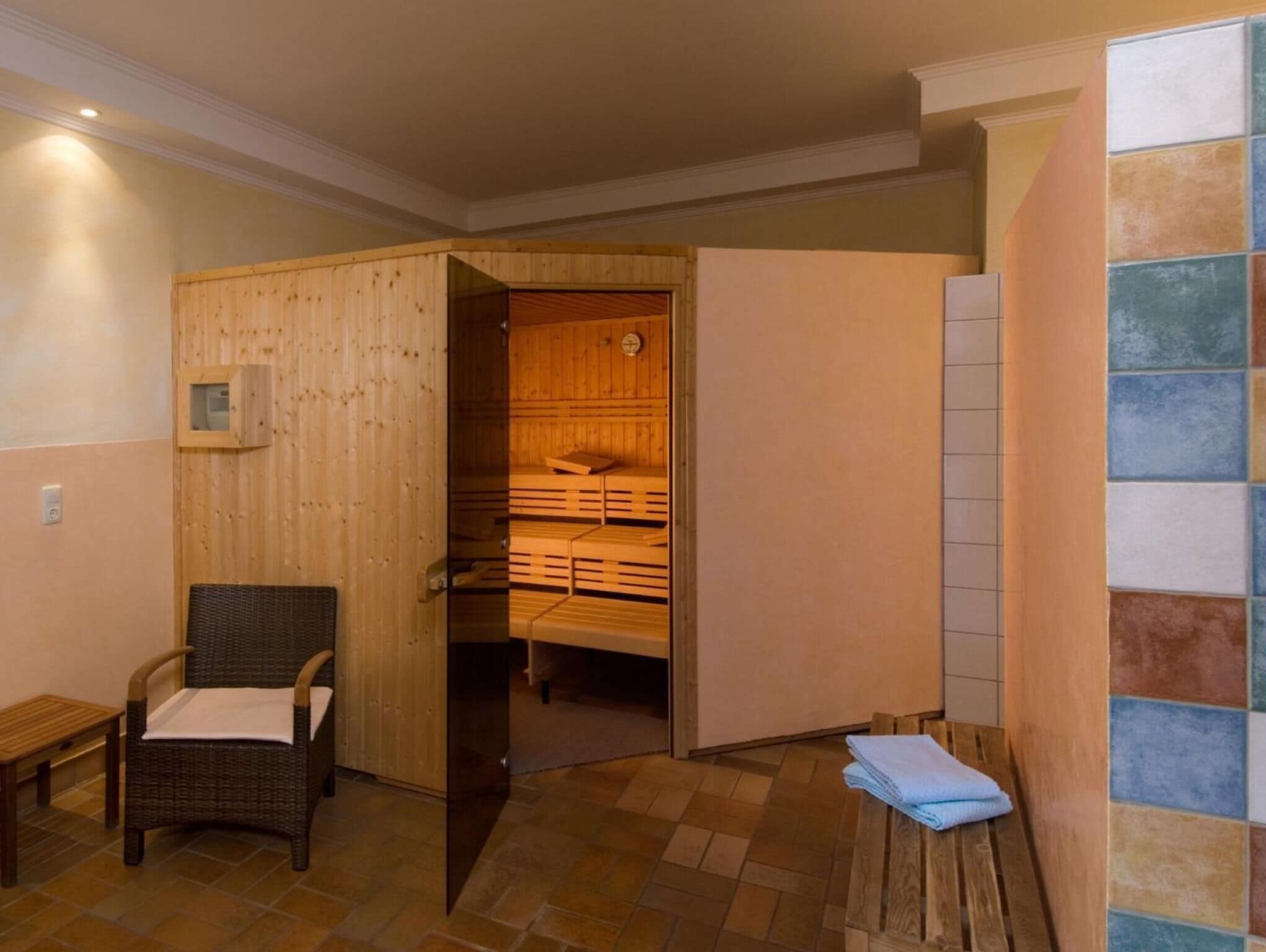 Un sauna avec des bancs en bois et un fauteuil en osier.
