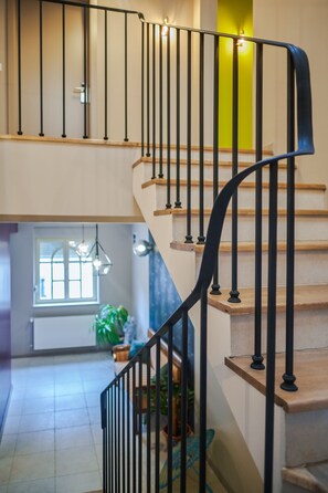 A staircase with black railings and wooden steps, leading to an upper floor.