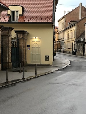 Straatbeeld met een gebouw met een traditionele gevel, een hekwerk en een heldere weg.