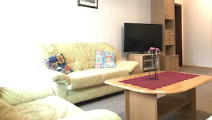 A living room with a sofa, a television, a small table, and a cabinet. - Ferienwohnungen Domizil (Bad Bertrich)