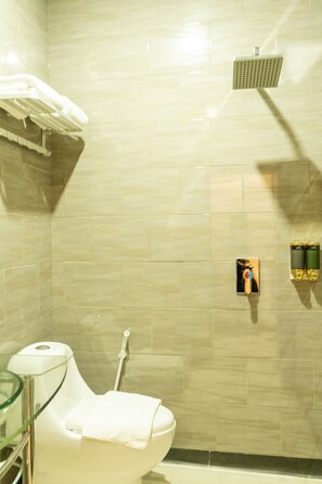A bathroom with a toilet, a glass shower enclosure, and a towel rack. - Hokkie Hotel Punggur Batam (Batam)