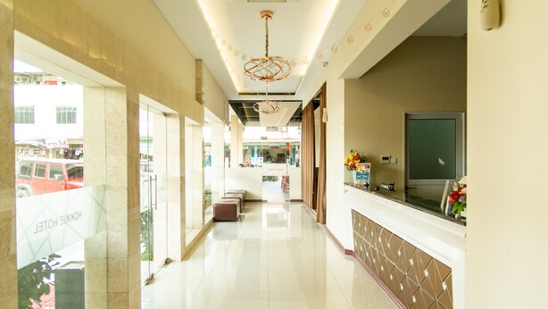 Een hotel receptiegebied met een modern design, inclusief een receptiebalie, zithoek en een groot raam met uitzicht op de straat.
