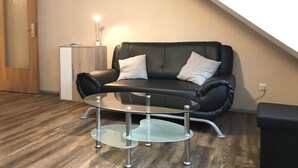 Un salon moderne avec un canapé en cuir noir, une table basse en verre et un meuble en bois.