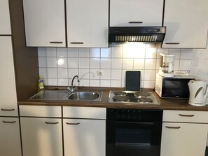 A modern kitchen with white cabinets, stainless steel appliances, a double sink, and a coffee maker.