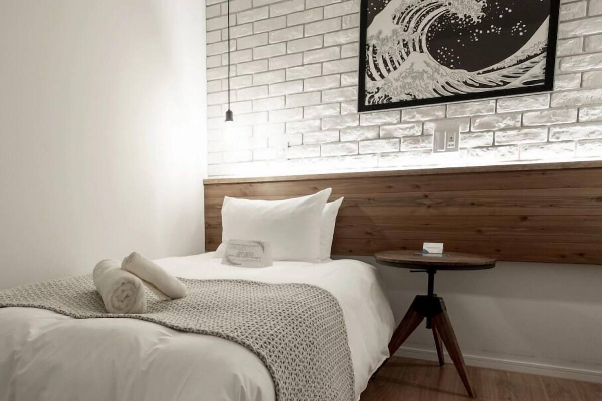 A hotel room with a bed, a small round table, and a wall-mounted artwork.