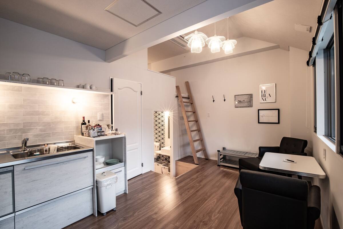 A modern kitchen with a built-in dishwasher, a white countertop, and a wooden floor.