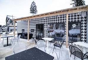 An outdoor café with black and white patterned walls, metal chairs, and tables.