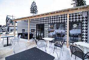 Relax in the open-air seating area with metal chairs and tables, surrounded by the building's traditional wooden beams and sloped roof.