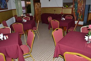 A dining area with tables and chairs, a patterned floor, and artwork on the walls. - Royal Basin Resort (Kumasi)