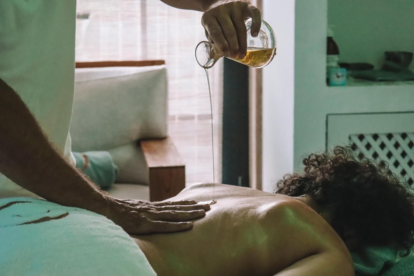 A person receiving a massage with a bottle of oil being poured.