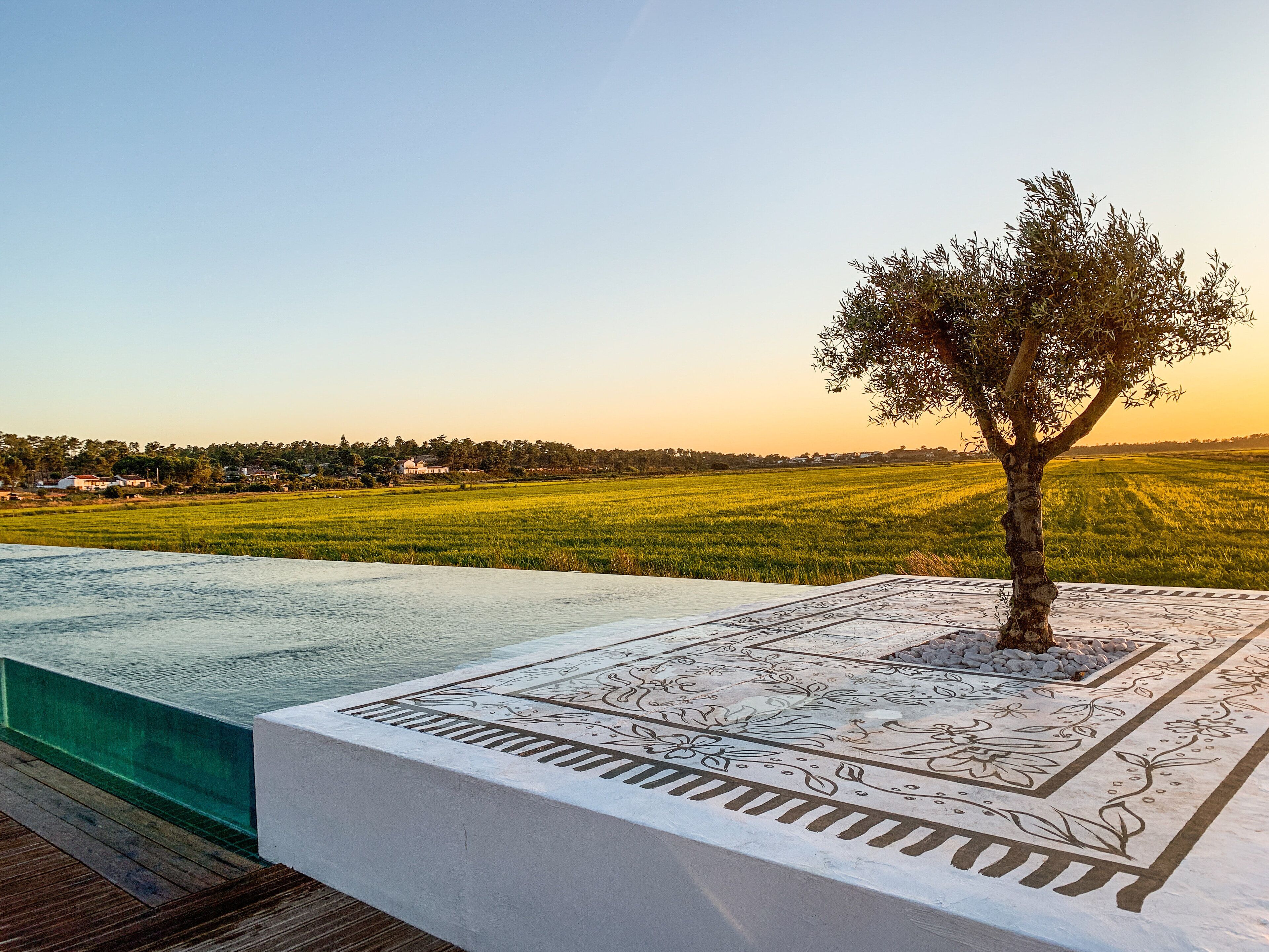 Una piscina con diseño geométrico, rodeada por una terraza de madera.
