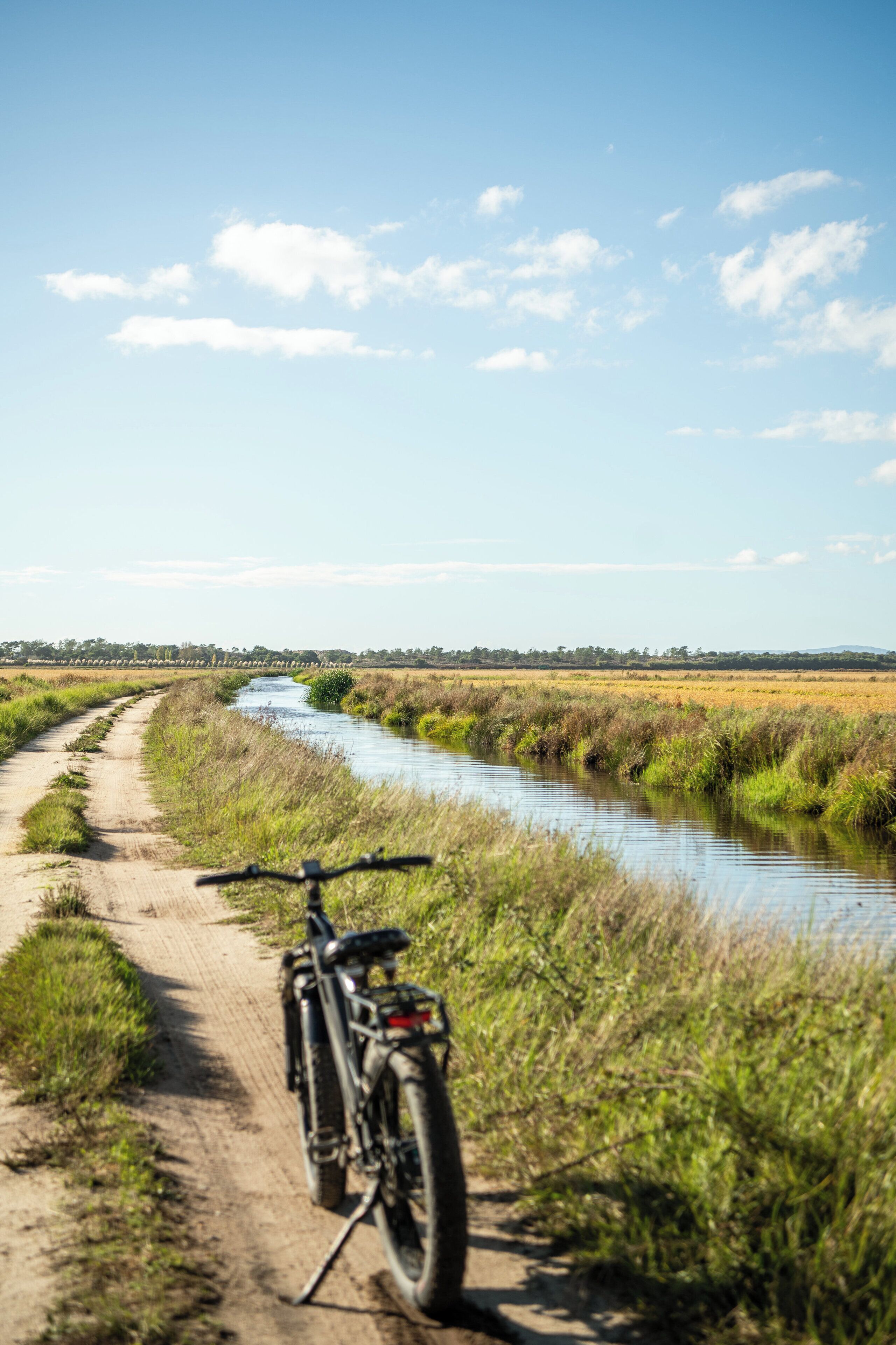Un sendero de tierra al lado de un canal con una bicicleta estacionada.