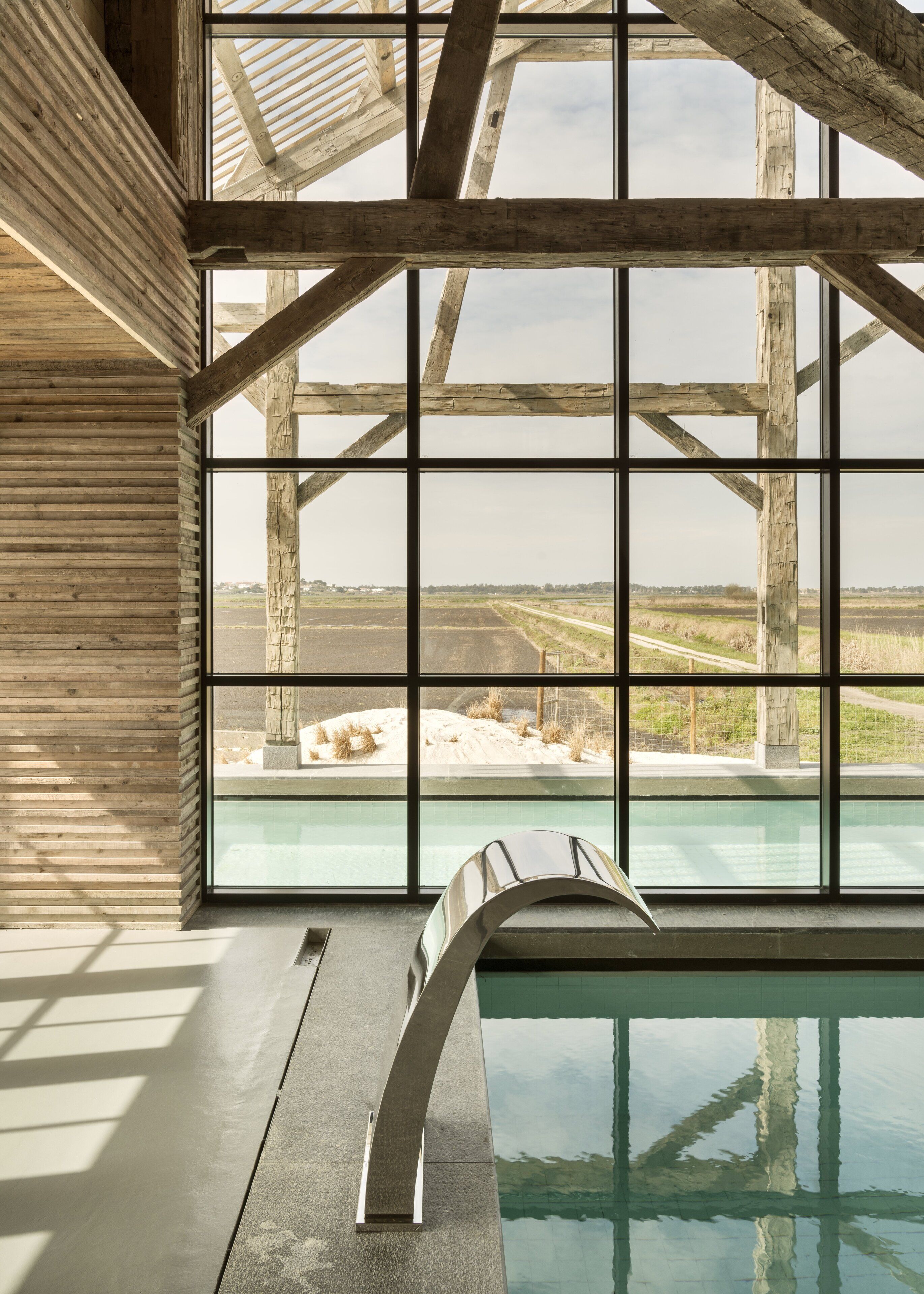 Una piscina interior moderna con vistas amplias del paisaje circundante a través de grandes ventanales.