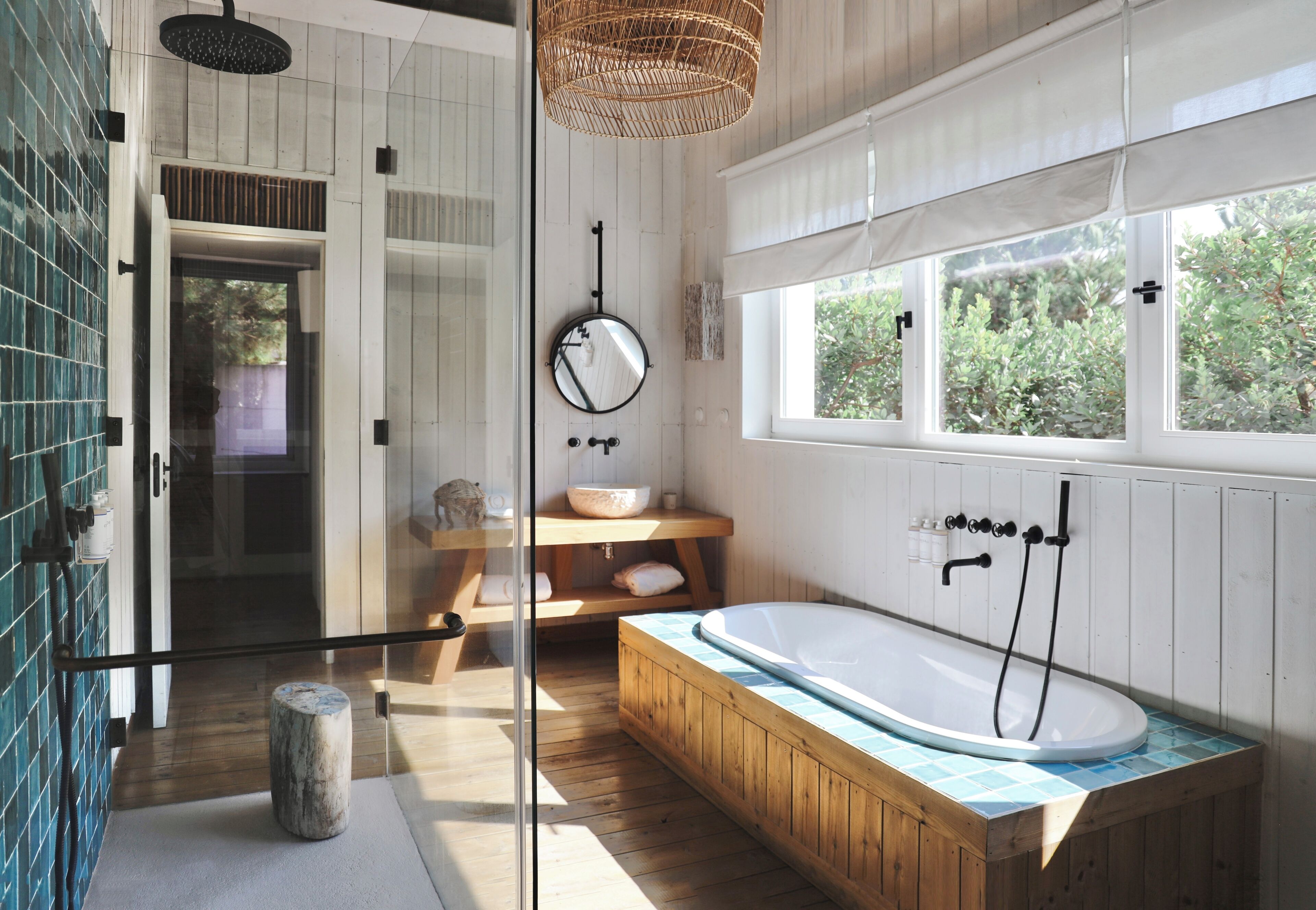 Une salle de bain moderne avec une baignoire sur pieds, une douche en verre et une grande fenêtre qui laisse entrer la lumière naturelle.