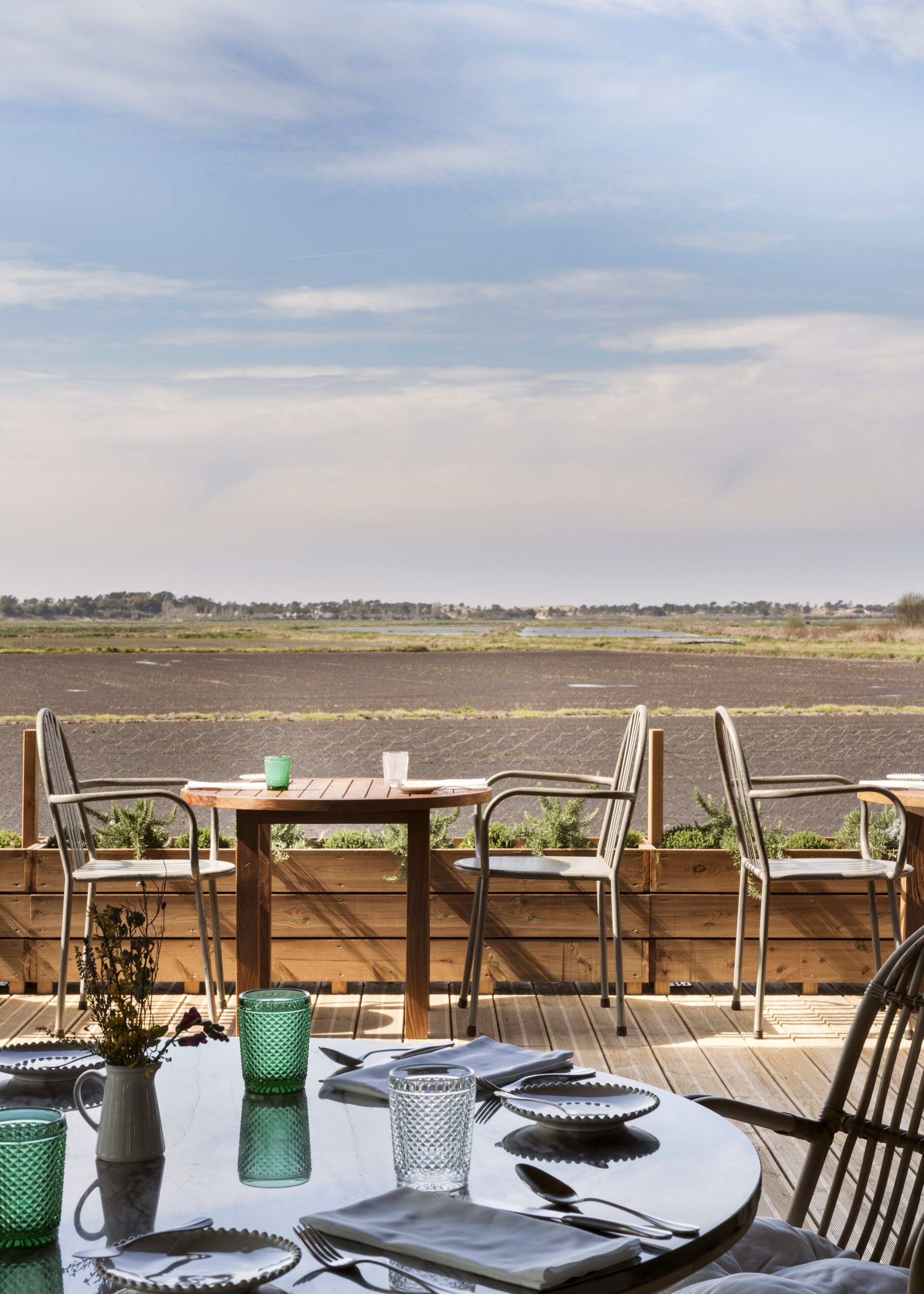 A wooden deck with a table set for two, overlooking a river.