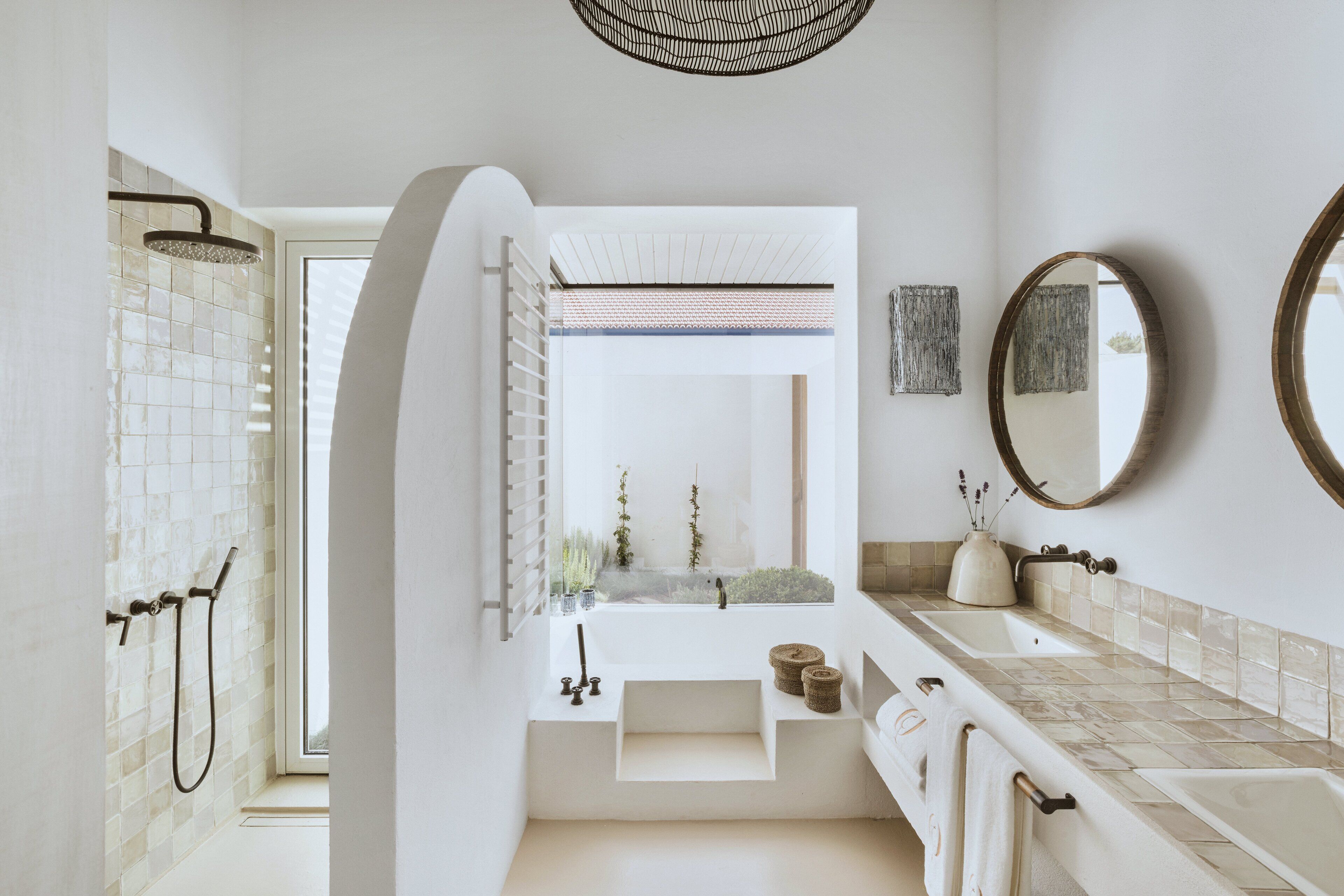 Un baño moderno con un ventanal grande, ducha, lavamanos y espejo.