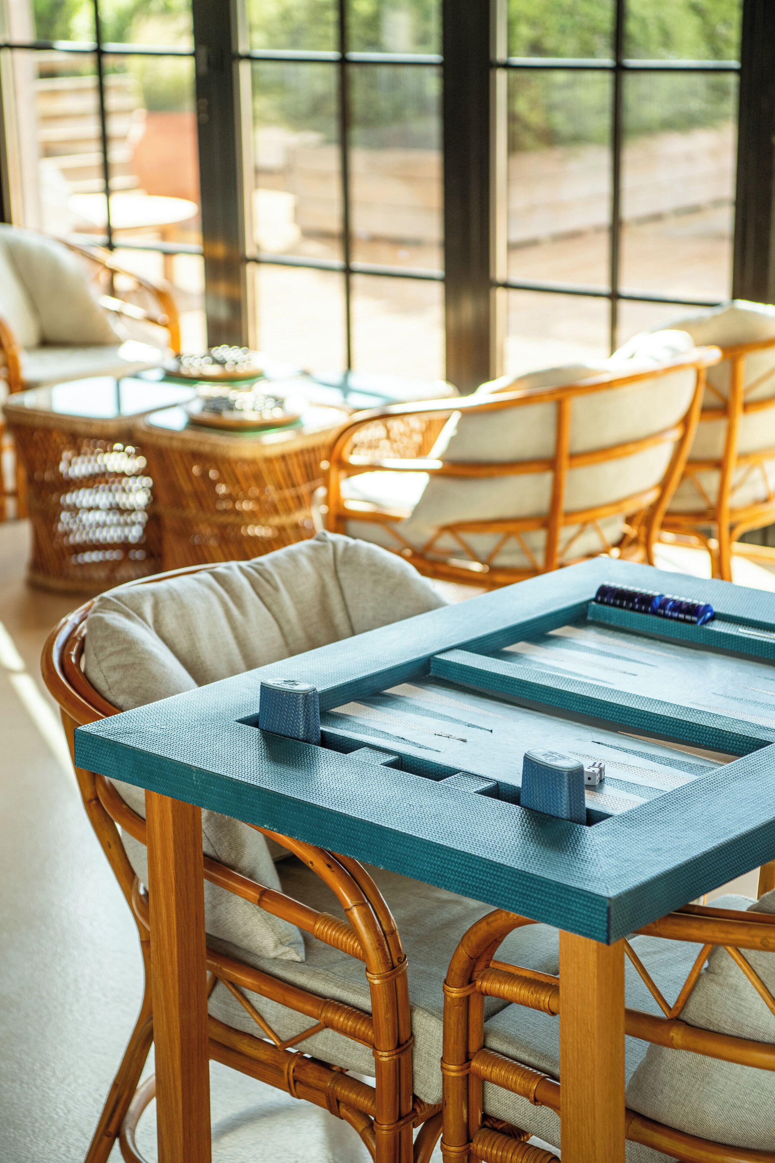 A wicker chair with a cushion, a table with a blue surface, and a wicker basket.