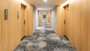 A hotel hallway with wooden walls and carpeted floors, leading to multiple doors with room numbers. - Country Inn & Suites by Radisson  (Shanghai)