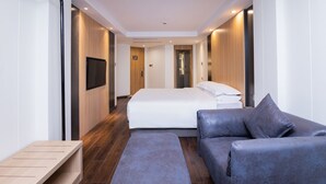 A modern hotel room with a large bed, a sofa, a TV, and a wooden bench. - Country Inn & Suites by Radisson  (Shanghai)
