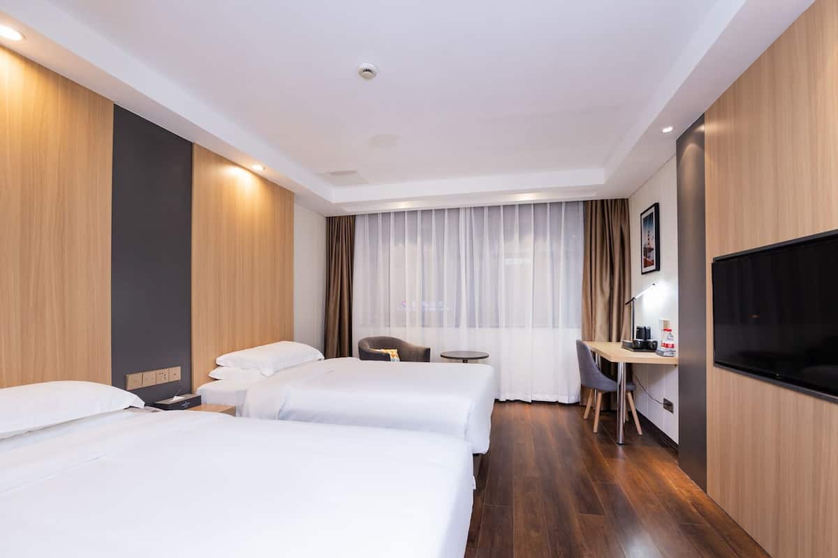 Habitación de hotel con dos camas, un escritorio, una silla, un televisor y una ventana con cortinas.