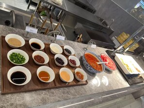 Un comptoir de buffet avec divers condiments et sauces présentés dans des bols.