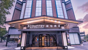 A hotel entrance with a modern design, featuring a large glass facade and a sign that reads "Country Inn & Suites by Radisson". - Country Inn & Suites by Radisson  (Shanghai)